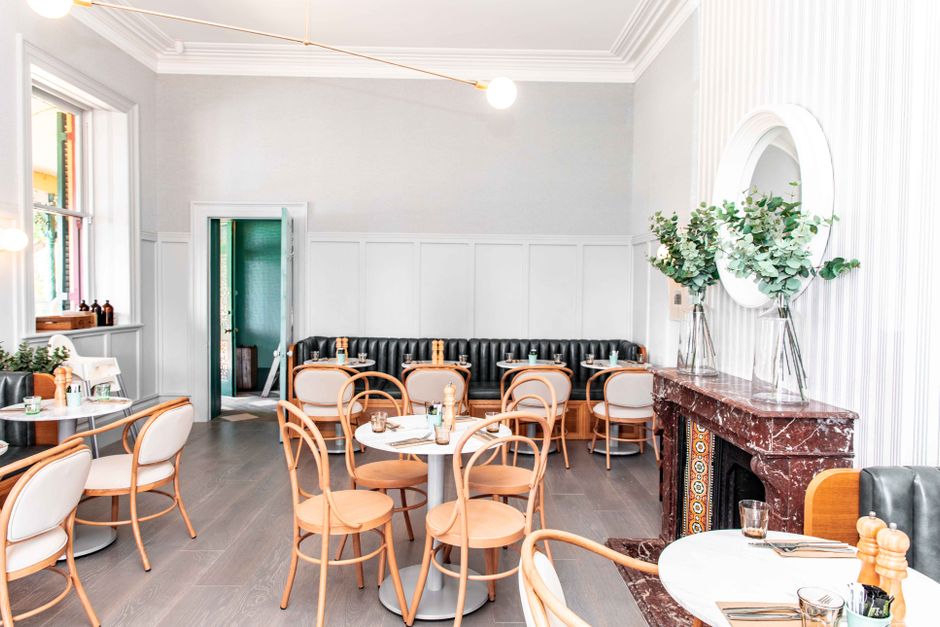 Ljus, stilren restauranginteriör med trästolar och dukade bord i skandinavisk stil