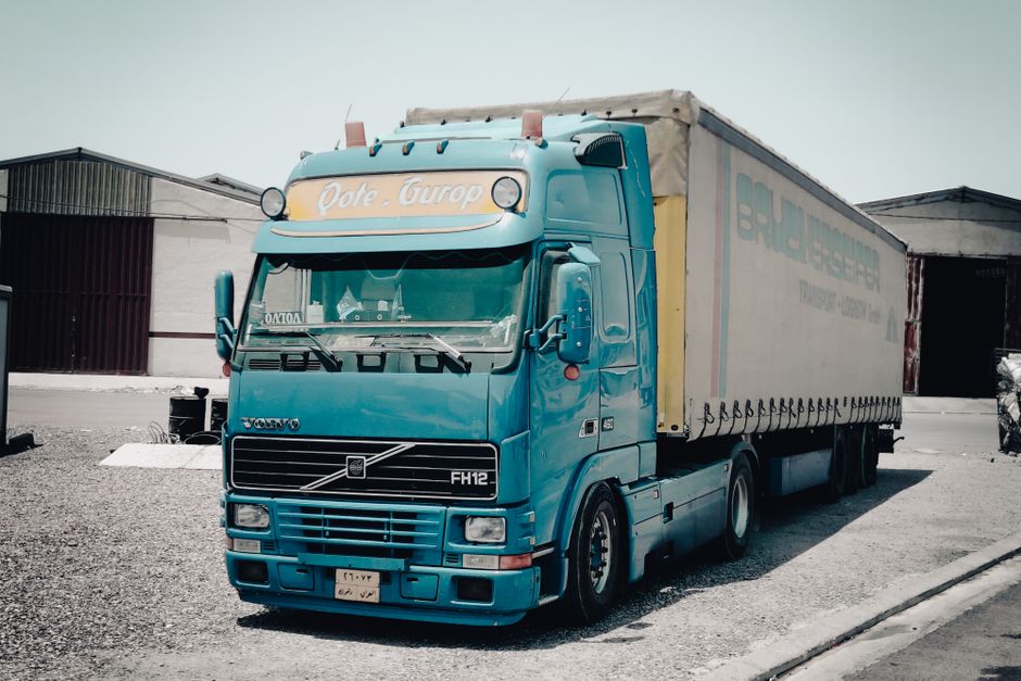 Blå lastbil parkerad utanför ett lager i ett industriområde i dagsljus