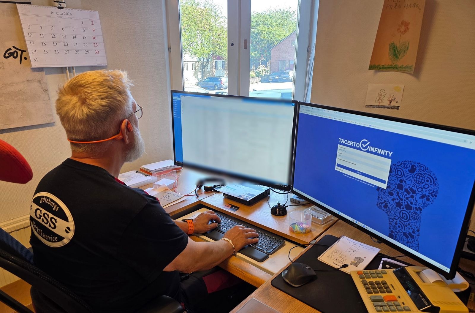 Tony Sommargren vid ett skrivbord med två skärmar, uppdragslistan i Mobigo på den ena och Tacerto Infinity på den andra